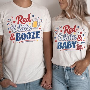 May include: Matching cream-colored t-shirts with patriotic designs. One shirt says "Red, White & BOOZE" with a beer mug graphic. The other says "Red, White & BABY Due 2026" with a pregnancy test graphic. Both shirts have red, white, and blue accents.