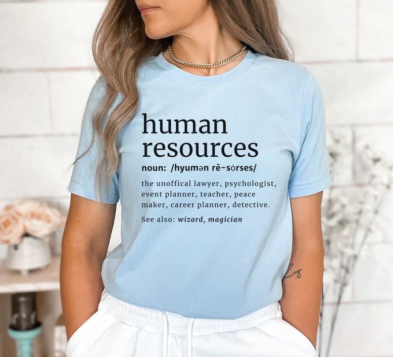May include: A light blue t-shirt with the words "human resources" in black, along with a definition and a list of related professions. The shirt is made of a soft material.