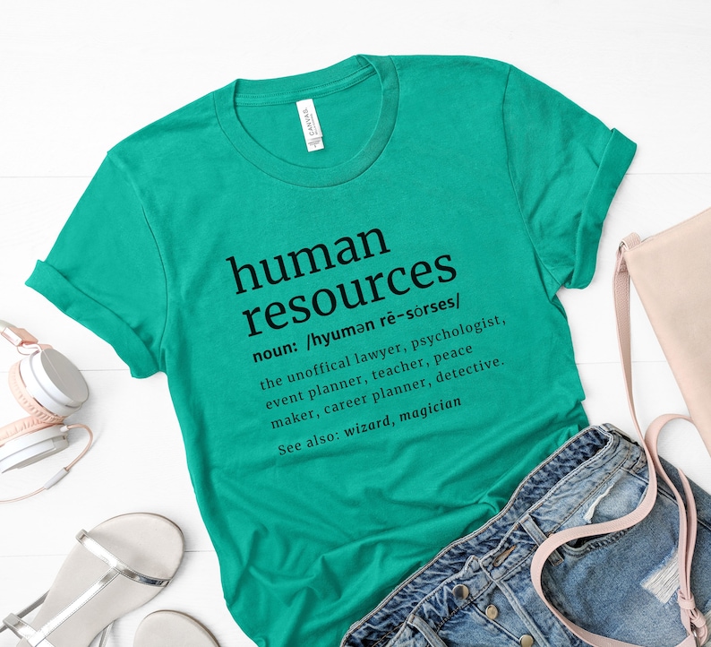 May include: A teal t-shirt with the words "human resources" printed in black, along with a definition. The definition includes the pronunciation and lists various roles. The shirt is folded at the sleeves.