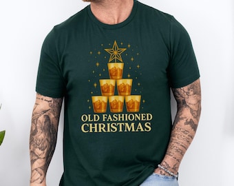 Könnte beinhalten: Dunkelgrünes T-Shirt mit einem weihnachtlichen Motiv. Es zeigt sechs Whiskeygläser, die als Weihnachtsbaum angeordnet sind und von einem Stern gekrönt werden. Der Text "OLD FASHIONED CHRISTMAS" ist darunter in Gold gedruckt.