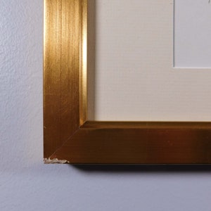 May include: Close-up of a gold picture frame with a slight chip on the corner.