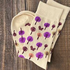May include: A pair of cream-coloured socks with a purple and brown tree pattern.