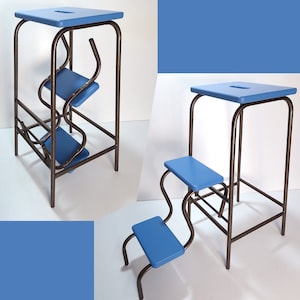 May include: A blue and bronze step stool with a square top and two curved steps. The frame is bronze-colored metal, and the steps and top are a solid blue. The stool has a unique, modern design.