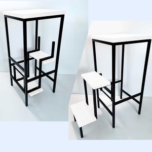 May include: Two white and black metal step stools. The larger stool has a rectangular top and a smaller stool is attached to the side. The smaller stool has three steps.