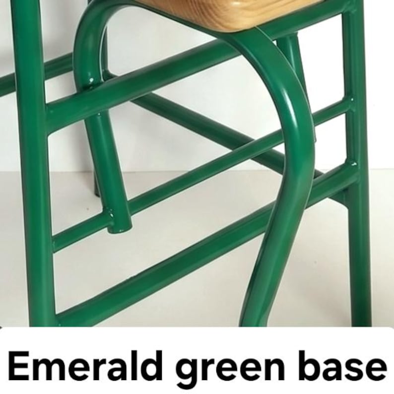 Op de afbeelding: Close-up van een stoelbasis met een smaragdgroen metalen frame. Het frame heeft gebogen en rechte lijnen, met een lichtgekleurde houten zitting aan de bovenkant. De tekst "Emerald green base" staat onderaan.