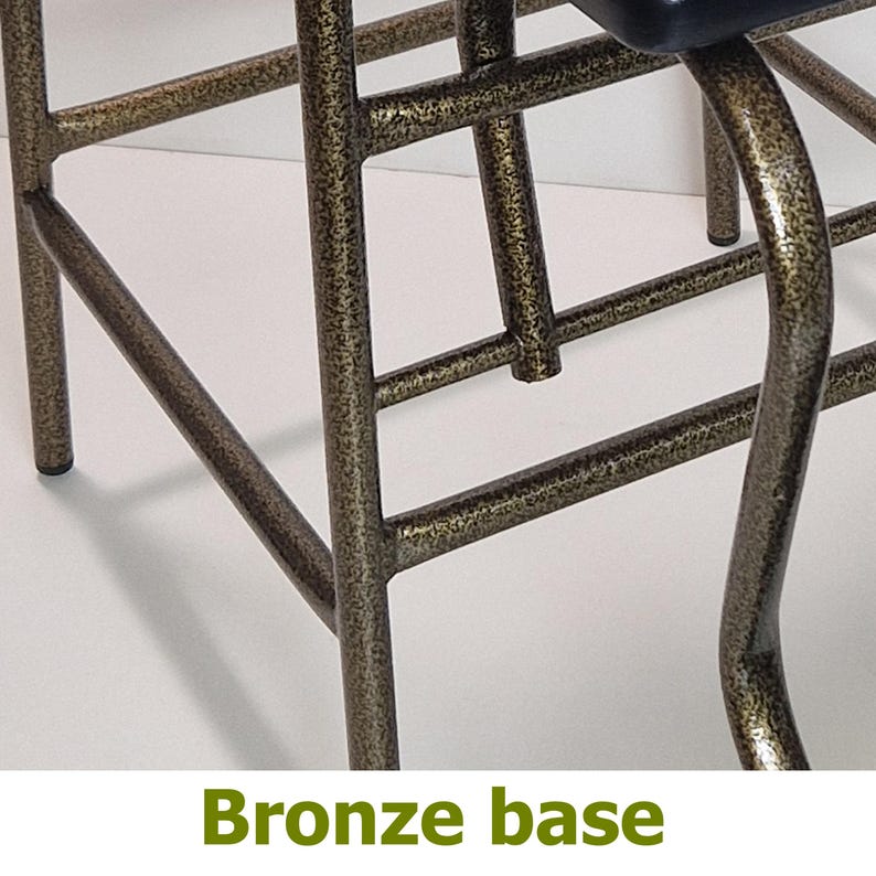 Op de afbeelding: Close-up van een bronzen metalen stoelbasis. De basis heeft een getextureerde afwerking en een netwerk van elkaar kruisende staven en gebogen steunen. De tekst "Bronze base" staat onderaan de afbeelding.