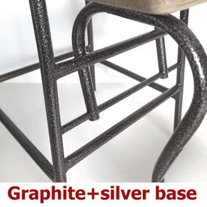 Op de afbeelding: Close-up van een grafiet en zilver metalen stoelbasis. Het metalen frame heeft een getextureerde afwerking en gebogen poten. De tekst "Graphite+silver base" staat onderaan de afbeelding.