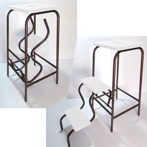 May include: A white metal step stool with two steps. The stool is made of a sturdy metal frame and has a white painted finish. The steps are also white and have a smooth surface.