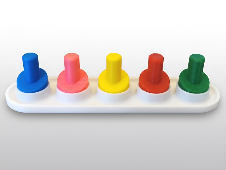 May include: A colorful toy featuring five pegs in blue, pink, yellow, red, and green. Each peg is a different color and sits on a white base. The pegs are cylindrical with a rounded top. The toy is designed for educational play.