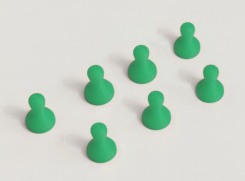 May include: Seven green game pieces arranged on a white surface. Each piece has a rounded base and a smaller, rounded top, resembling a person. The pieces are evenly spaced, creating a pattern.