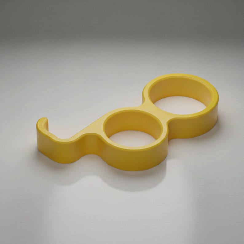 May include: A yellow bottle opener with a unique design. It features two circular openings connected by a curved handle and a hook-shaped end. The opener is made of a solid, smooth material.