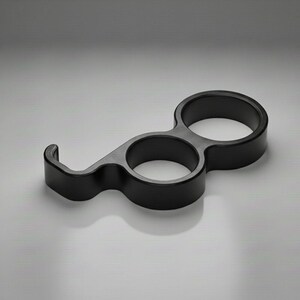 May include: A black, sculptural bottle opener with a unique design. It features two circular openings and a curved hook, all in a matte finish. The opener is designed for easy handling and a modern aesthetic.