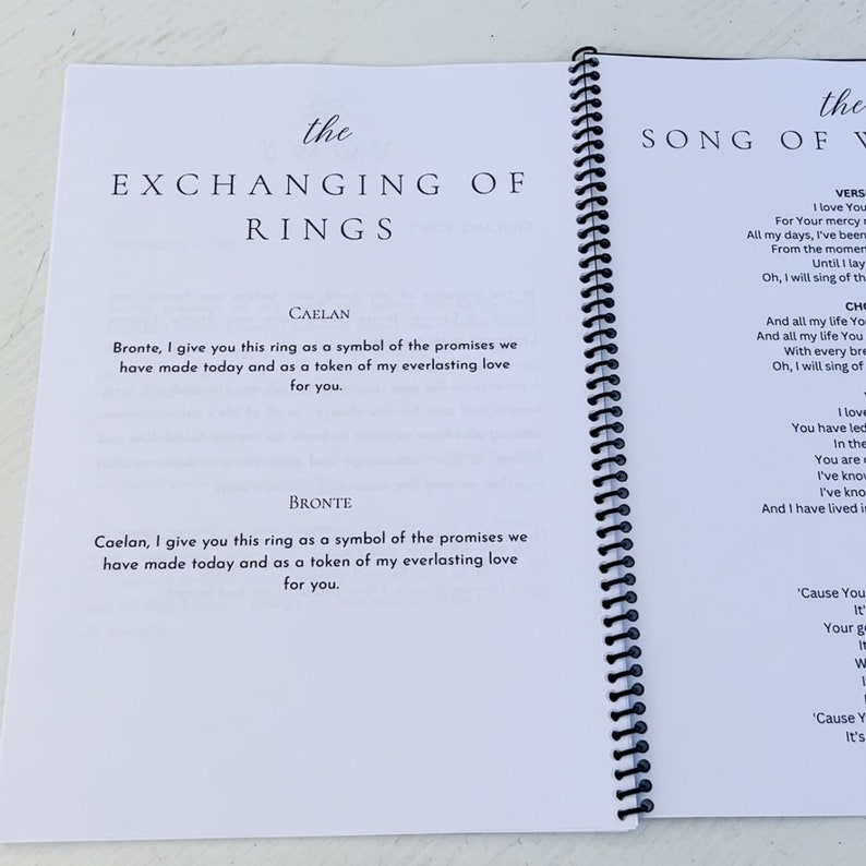 Puede incluir: Un folleto blanco con una encuadernaci&oacute;n en espiral negra. La portada tiene el texto "the EXCHANGING OF RINGS" en negro. La contraportada tiene el texto "the SONG OF" en negro. El folleto contiene votos para una ceremonia de boda.