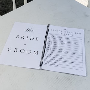 Puede incluir: Un planificador de boda blanco y negro con las palabras "the bride + groom" en la portada y un cronograma detallado en la contraportada.