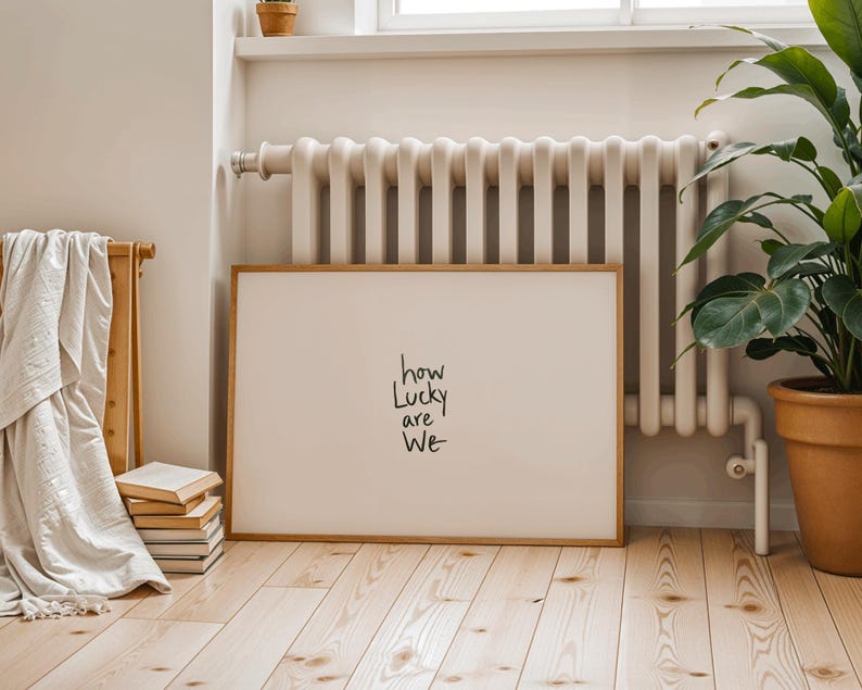 A minimalist wall art print featuring the quote “How Lucky Are We” in elegant hand-drawn typography on a neutral background. The modern canvas design exudes warmth and simplicity, perfect for couples who value love and gratitude. This inspirational quote poster adds a timeless touch to any contemporary or boho-style home. A beautifully crafted neutral wall decor piece that symbolizes appreciation, connection, and modern elegance.