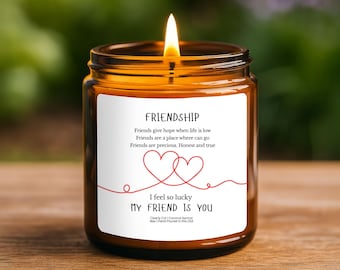 Peut inclure: Une bougie allumée dans un pot en verre ambré avec une étiquette blanche portant le texte Friendship, un poème sur les amis, deux cœurs rouges dessinés au trait et le texte I feel so lucky MY FRIEND IS YOU, avec Clearly Cut Coconut Apricot Wax.