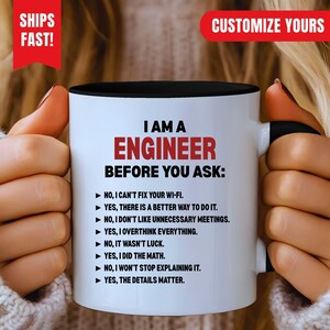 May include: A white ceramic mug with a black interior and handle, featuring the black text I AM A ENGINEER BEFORE YOU ASK followed by a list of eight statements starting with arrows, including I can't fix your Wi-Fi and I did the math.