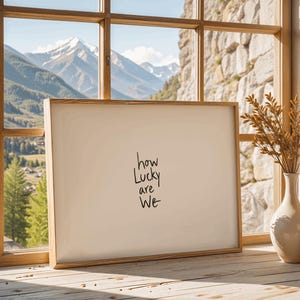 A minimalist wall art print featuring the quote “How Lucky Are We” in elegant hand-drawn typography on a neutral background. The modern canvas design exudes warmth and simplicity, perfect for couples who value love and gratitude. This inspirational quote poster adds a timeless touch to any contemporary or boho-style home. A beautifully crafted neutral wall decor piece that symbolizes appreciation, connection, and modern elegance.