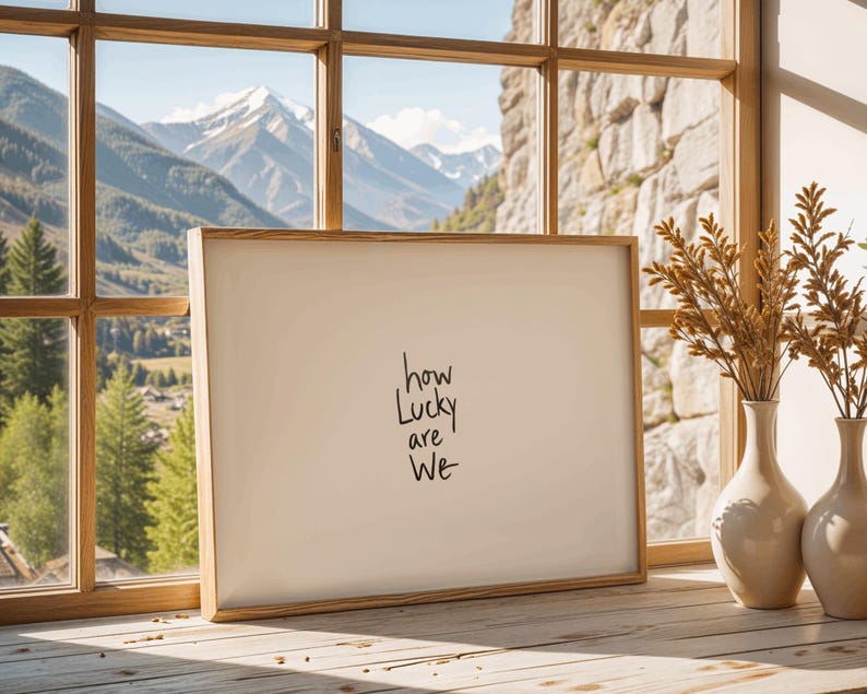 A minimalist wall art print featuring the quote “How Lucky Are We” in elegant hand-drawn typography on a neutral background. The modern canvas design exudes warmth and simplicity, perfect for couples who value love and gratitude. This inspirational quote poster adds a timeless touch to any contemporary or boho-style home. A beautifully crafted neutral wall decor piece that symbolizes appreciation, connection, and modern elegance.