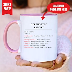 May include: White ceramic mug with a pink interior and handle. The mug features the text "DIAGNOSTIC REPORT" and a list of humorous health-related statements. The mug is personalized with the name "OLIVIA" and age "60".