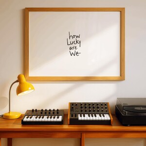 A minimalist wall art print featuring the quote “How Lucky Are We” in elegant hand-drawn typography on a neutral background. The modern canvas design exudes warmth and simplicity, perfect for couples who value love and gratitude. This inspirational quote poster adds a timeless touch to any contemporary or boho-style home. A beautifully crafted neutral wall decor piece that symbolizes appreciation, connection, and modern elegance.