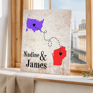 May include: A canvas print featuring a map of the United States and Wisconsin, connected by a dotted line. The United States is purple, Wisconsin is red, and both have a black heart. The names "Nadine & James" are printed below.