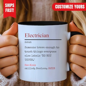 Puede incluir: Una taza de cerámica blanca con interior y asa negros, con texto en negro y rojo que define a un electricista como alguien lo suficientemente valiente para tocar cosas que otros etiquetan como NO TOCAR, incluyendo la mención de JACOB.
