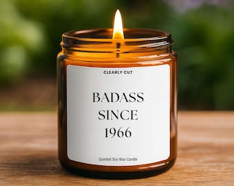 Peut inclure: Une bougie allumée dans un pot en verre ambré avec une étiquette blanche. L'étiquette porte le texte CLEARLY CUT, BADASS SINCE 1966 et Scented Soy Wax Candle en polices noires. La bougie possède une mèche allumée avec une flamme vive.