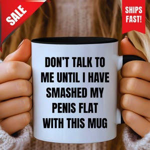 May include: White ceramic mug with a black interior and handle. The mug features the text "DON'T TALK TO ME UNTIL I HAVE SMASHED MY PENIS FLAT WITH THIS MUG" in bold black letters. A red "SALE" banner is in the upper left corner and a red "SHIPS FAST!" banner is in the upper right corner.