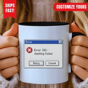 Può includere: Una tazza in ceramica bianca con interno e manico neri, caratterizzata da un messaggio di errore del computer stampato che recita Error, Error 101: Adulting Failed, con un'icona circolare rossa con una X bianca e due pulsanti Retry e Cancel.