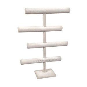May include: White wooden jewelry stand with four tiers of padded rods for displaying bracelets and bangles. The stand has a square base and the text "THE ART OF DISPLAY" is printed on the bottom rod.