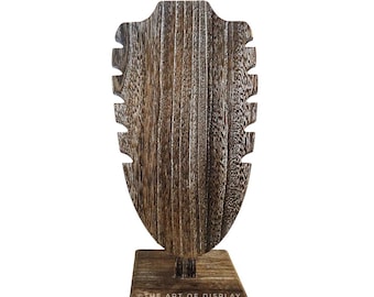 May include: Wooden necklace display stand with a brown wood finish and a rectangular base. The stand has a cutout in the shape of a neck to hold necklaces. The stand is labeled "The Art of Display".