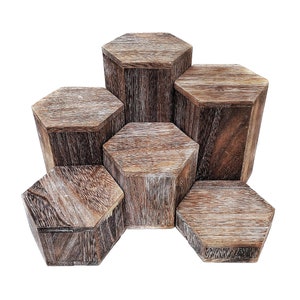 May include: Six wooden, hexagonal display blocks with a natural, weathered finish. The blocks vary in height and are arranged in a cluster, showcasing the wood grain and texture. The color is a mix of light and dark brown.