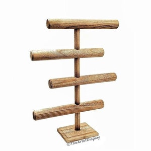 May include: Wooden bangle stand with four tiers for displaying bracelets. The stand has a square base and is made of natural wood.