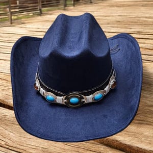 May include: A dark blue cowboy hat with a white band and turquoise stones. The hat has a wide brim and a pointed crown.