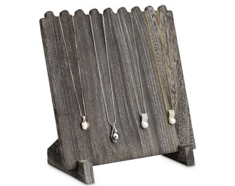 May include: A wooden jewelry display stand with a gray finish, holding four necklaces. The necklaces have different pendants, including a pink stone, a silver teardrop, a pearl, and a gold pendant with a pearl.