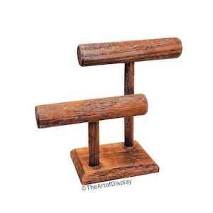 May include: Wooden bracelet display stand with two horizontal bars for holding bracelets. The stand has a square base and is made of dark brown wood.
