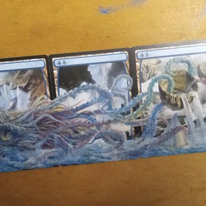 May include: A series of four trading cards featuring a detailed illustration of a sea monster with multiple tentacles emerging from the water. The artwork is predominantly blue, purple, and white, with a mountainous background.