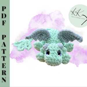 May include: A crocheted dragon in shades of mint green and gray, with large, expressive eyes. The dragon has wings and is lying down. The image includes the text "PDF PATTERN" on the left and a logo that says "Kai's Kreations".