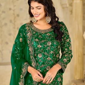 Pu&ograve; includere: Una tunica verde smeraldo a maniche lunghe con intricati ricami floreali dorati e decorazioni di paillettes sul corpetto e sulle maniche, abbinata a una dupatta verde trasparente coordinata con un bordo ricamato decorativo.