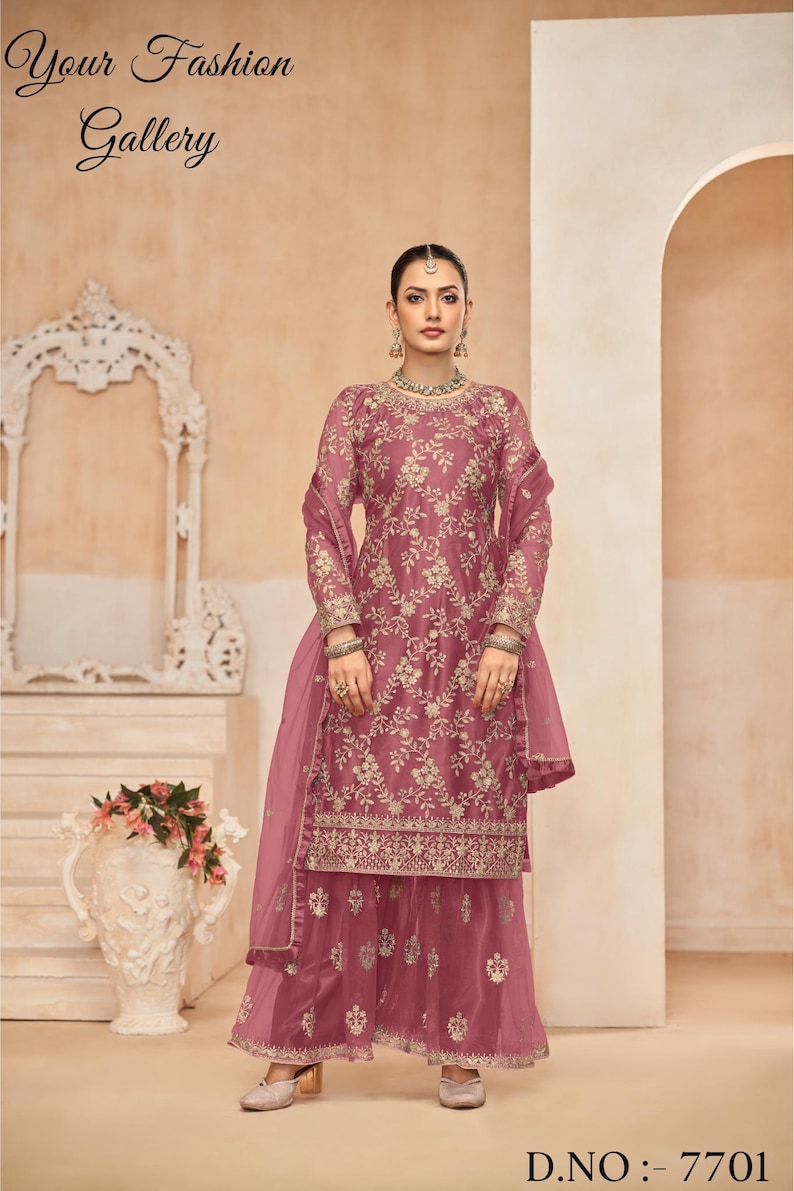 Op de afbeelding: Een roze geborduurde jurk met een bijpassende dupatta en palazzo broek. De jurk heeft een bloemenmotief en gouden borduurwerk. De dupatta is doorschijnend en heeft een gouden rand. De palazzo broek is wijd en heeft een gouden rand. D.NO: 7701