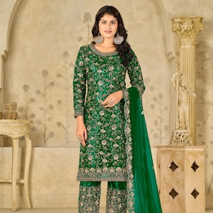 Pu&ograve; includere: Un completo composto da una tunica a maniche lunghe e pantaloni corti color verde smeraldo, caratterizzato da intricati ricami floreali argentati, paillettes e perline. L'insieme include una dupatta verde trasparente con bordo ricamato.