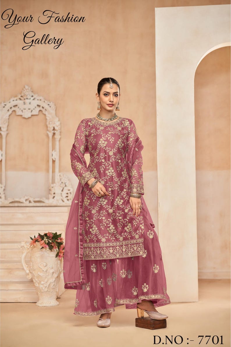 Op de afbeelding: Een roze geborduurde jurk met een bijpassende dupatta en palazzo broek. De jurk heeft een bloemenmotief en gouden borduurwerk. De outfit is perfect voor een speciale gelegenheid.