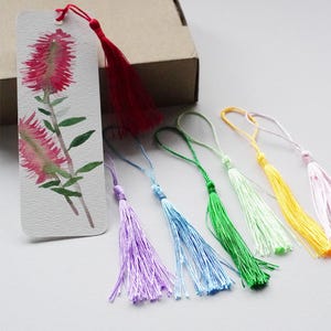 May include: A set of ten colorful tassel bookmarks with a watercolor floral design. The bookmarks are made of silk and have a variety of colors, including purple, blue, green, yellow, and pink.