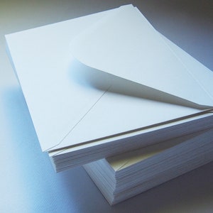 May include: A stack of white envelopes with a single envelope partially opened, revealing the inside of the envelope.