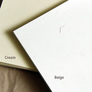 Op de afbeelding: Twee vellen papier, een cr&egrave;me en een beige, liggen op elkaar. Het cr&egrave;me papier ligt onderop en het beige papier ligt bovenop. Het beige papier is iets groter dan het cr&egrave;me papier.