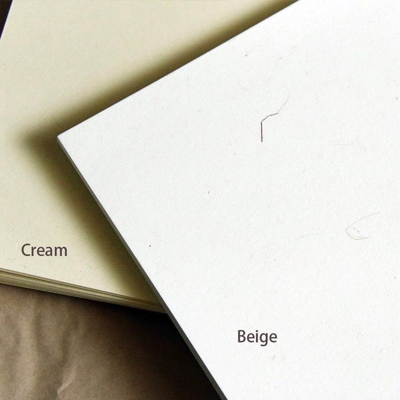 Op de afbeelding: Twee vellen papier, een cr&egrave;me en een beige, liggen op elkaar. Het cr&egrave;me papier ligt onderop en het beige papier ligt bovenop. Het beige papier is iets groter dan het cr&egrave;me papier.
