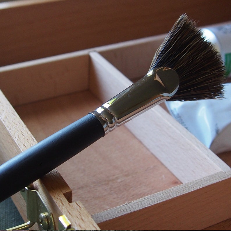 May include: A black handled fan brush with silver ferrule and natural bristles. The brush is in a wooden box.