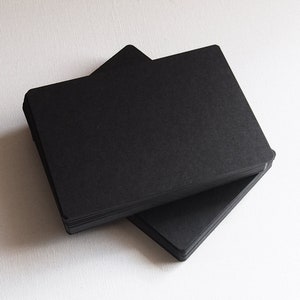 May include: A stack of black card stock paper. The paper is smooth and has a matte finish.