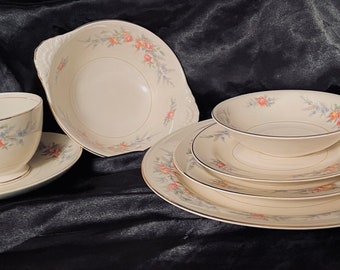 May include: A set of vintage floral patterned china, including a teacup and saucer, a small bowl, and three plates. The china is white with a delicate floral design in shades of pink, blue, and green.